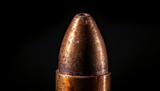macro view of aged bullet with engraved markings and textured metallic surface against dark background photo