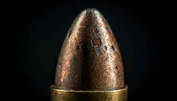 macro close-up of an aged bullet with visible corrosion and metallic texture against dark background photo