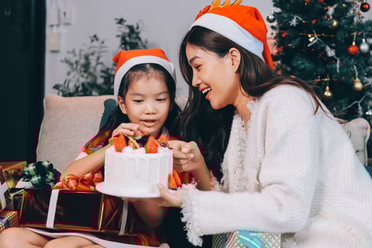 Merry Christmas and Happy Holidays. Cheerful mom and her cute daughter girl exchanging gifts. Parent and little child having fun near tree indoors. photo