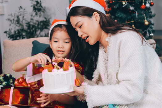 Merry Christmas and Happy Holidays. Cheerful mom and her cute daughter girl exchanging gifts. Parent and little child having fun near tree indoors. photo