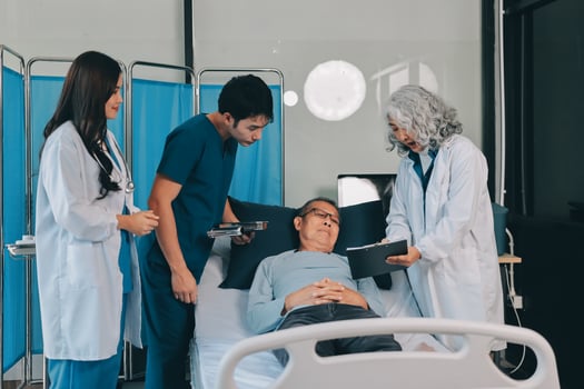 A group of doctors and nurses standing around a patient in a hospital bed photo