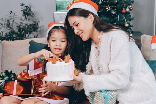 Merry Christmas and Happy Holidays. Cheerful mom and her cute daughter girl exchanging gifts. Parent and little child having fun near tree indoors. photo