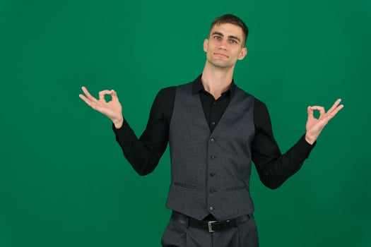 young businessman feeling successful and satisfied, smiling with mouth wide open, making okay sign with hand against green background photo