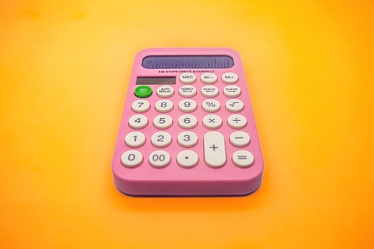 A bright pink calculator with large buttons and a clear display, set against a vibrant yellow background. Perfect for school, office, or everyday use photo