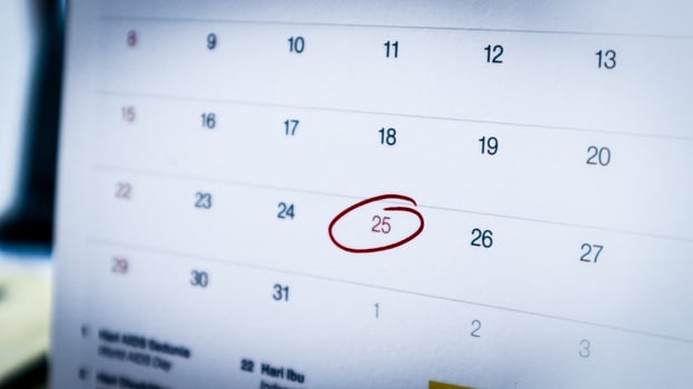 close-up of December 25, 2024, on an office calendar, circled in red marker to indicate a holiday, with a blurred office workspace in the background. photo