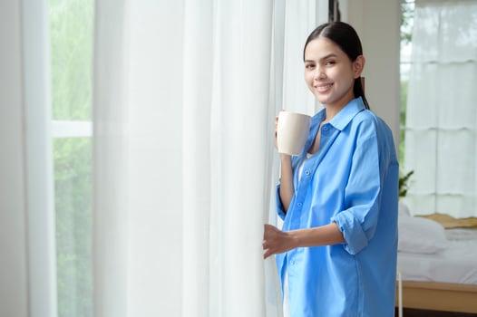 Morning Routine in a Bright Bedroom With a Woman Enjoying Coffee by the Window photo