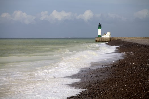 Lighthouse on a French coast with waves and rocky shore. Tranquility and solitude of coastal landscapes. photo