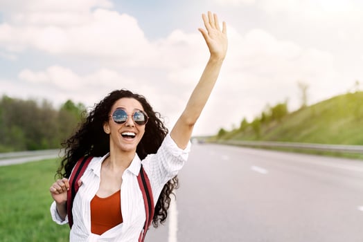 Adventure and tourism concept. Beautiful millennial woman in casual wear waving down car, hitchhiking on roadside, copy space. Pretty young lady traveling by autostop, having summer trip photo