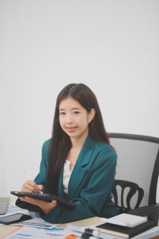 Beautiful Asian businesswoman work using a tablet and a laptop with documents placed at the office. photo