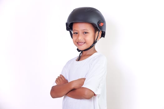 A young asian boy smiles confidently while wearing a helmet and a white shirt. photo