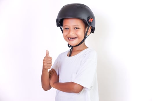 A cheerful asian boy in a helmet gives a thumbs up, showing his excitement for safety. photo