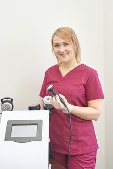 Female caucasian adult in maroon scrubs holding medical device in clinic setting. photo