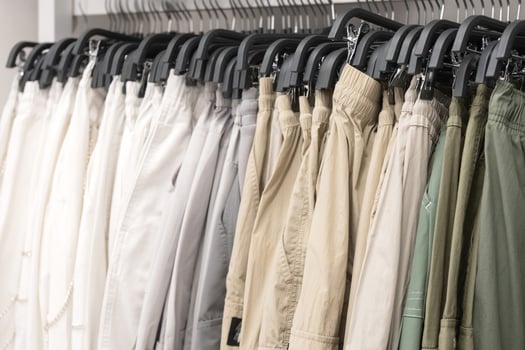 Neutral-toned pants hanging on racks in a clothing store. Retail display photography for fashion photo