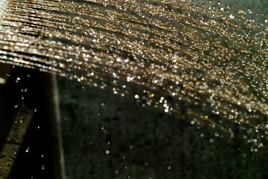Water droplets glisten on a dark surface under bright light photo