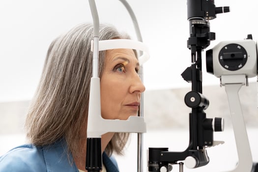Senior woman undergoing eye exam with slit lamp in ophthalmology clinic photo