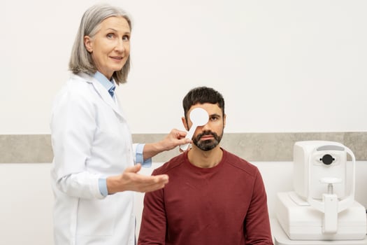 Senior female doctor performing eye exam on male patient in ophthalmology clinic photo