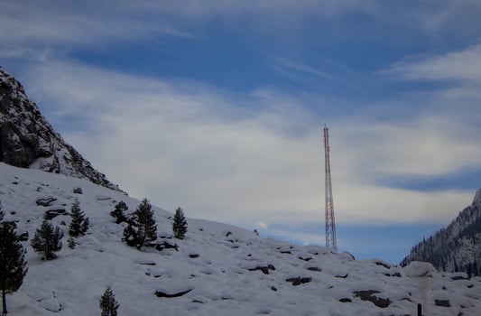 Snowy Mountain Landscape with Communication Tower under Blue Sky photo