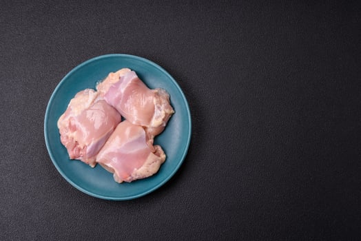 Fresh raw chicken thigh fillets with salt, spices and herbs photo