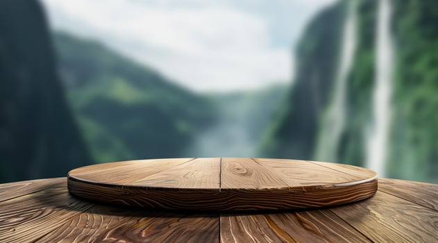 A wooden round platform on a wooden table with a blurred background of a lush green valley and waterfalls. photo