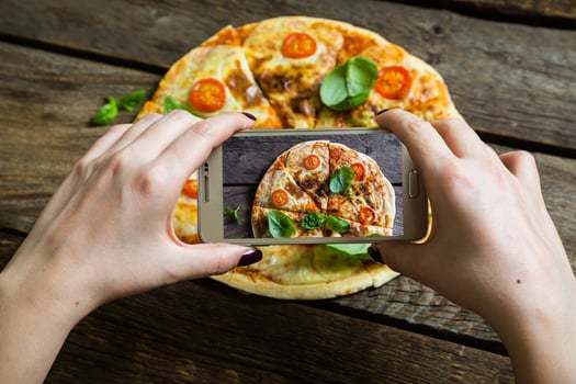 Girl photographs pizza on your smartphone photo