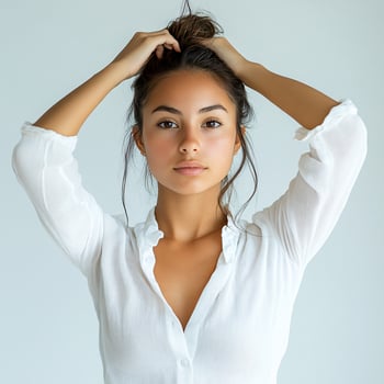 A woman in a white shirt is holding her hair photo