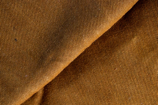 Close up detail folded bright brown jeans fabric background texture. photo
