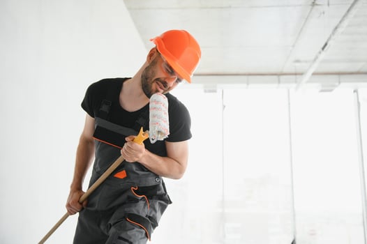 Funny and cheerful worker sings in a roller for painting the walls photo