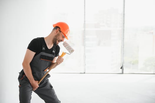 Funny and cheerful worker sings in a roller for painting the walls photo