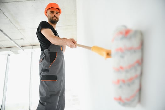 Building contractor painting grey wall with roller brush photo