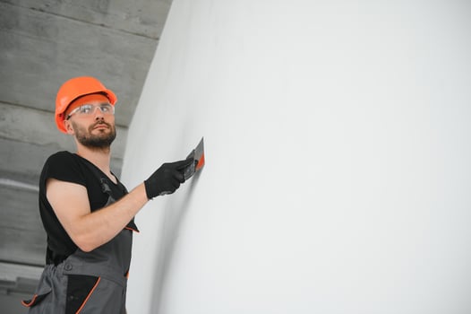 Tradesman on stilts plastering drywall in home photo