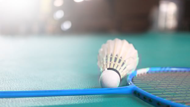 White badminton shuttlecocks and badminton rackets on green floor indoor badminton court. Concept for badminton competition and its lovers. photo