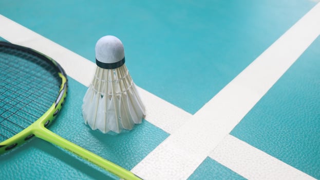 White badminton shuttlecocks and badminton rackets on green floor indoor badminton court. Concept for badminton competition and its lovers. photo