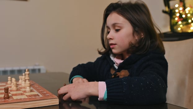 Young girl focused on playing chess game at cozy indoor setup photo