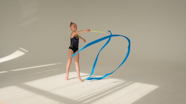 Young little girl child kid schoolgirl daughter female ballerina dancer acrobat gymnast swirling spinning with gymnastic ribbon artistic sport exercise choreography children dance ballet school studio photo