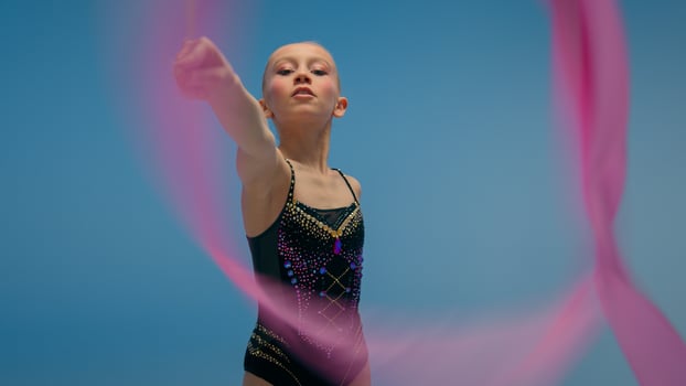Caucasian little girl kid daughter schoolgirl female gymnast schoolgirl child dancer ballerina athlete perform gymnastics exercise twirling spinning gymnastic tape dance ballet studio blue background photo