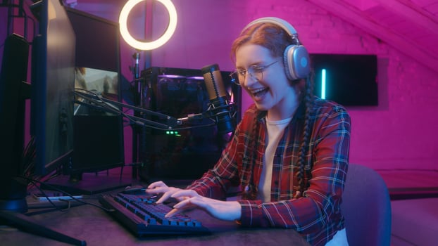 Happy gen z influencer blogger streamer teen woman girl female gamer player headphones neon light play computer game racing cyber sport competition online stream gaming addict playing keyboard photo