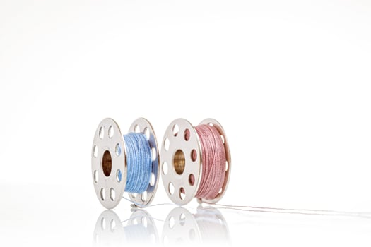 spools of blue and pink thread on a white background photo
