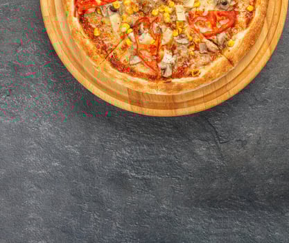 delicious pizza with chicken, mushrooms, cheese, tomatoes and corn on a concrete background photo