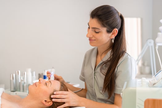 Smiling female cosmetologist applying iontophoresis on client's face photo