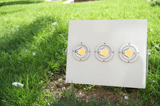 An Outdoor Spotlight Fixture placed on a lush Green Grass area showcasing intense illumination photo