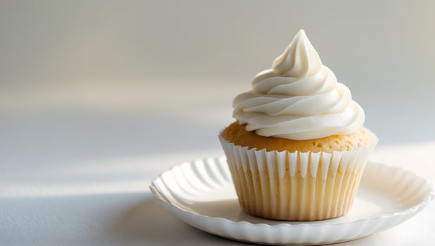 A cupcake with white frosting on a white plate photo