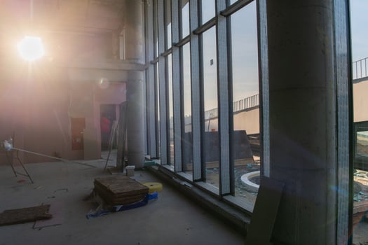 A captivating view of a modern business building under construction, showcasing its raw industrial interior with exposed steel beams and concrete walls bathed in the warm, golden hues of a sunset photo