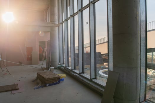 A captivating view of a modern business building under construction, showcasing its raw industrial interior with exposed steel beams and concrete walls bathed in the warm, golden hues of a sunset photo