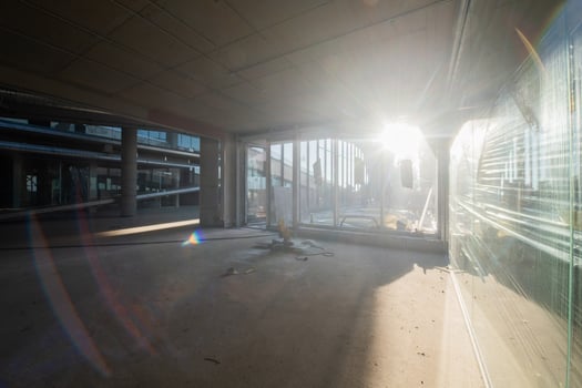 A captivating view of a modern business building under construction, showcasing its raw industrial interior with exposed steel beams and concrete walls bathed in the warm, golden hues of a sunset photo