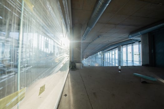 A captivating view of a modern business building under construction, showcasing its raw industrial interior with exposed steel beams and concrete walls bathed in the warm, golden hues of a sunset photo