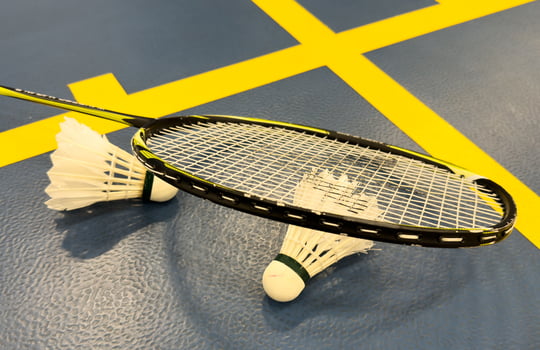 Shuttlecock on badminton racquet on floor. photo