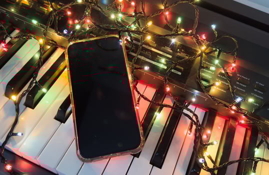 Piano keyboard and Christmas tree illuminations. smartphone, Holidays concept photo