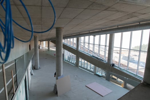 A captivating view of a modern business building under construction, showcasing its raw industrial interior with exposed steel beams and concrete walls bathed in the warm, golden hues of a sunset photo