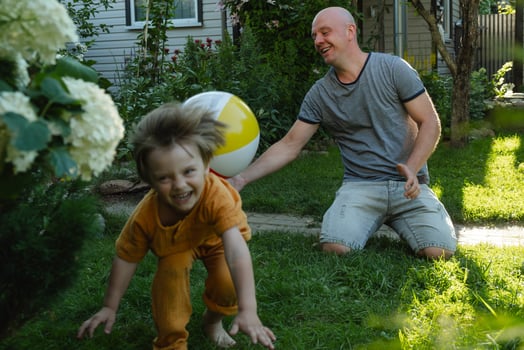 Summer outdoor activities, family time. Father and son having fun playing with inflatable ball in backyard. photo