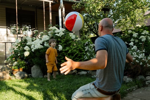 Summer lawn games, father day concept. Family having fun playing with inflatable ball in backyard. photo